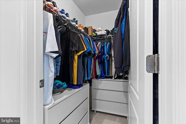 a view of walk in closet with clothes and shoes