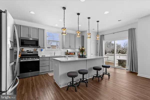 a kitchen with stainless steel appliances a dining table chairs stove and a wooden floor