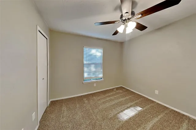 en empty room with windows and ceiling fan