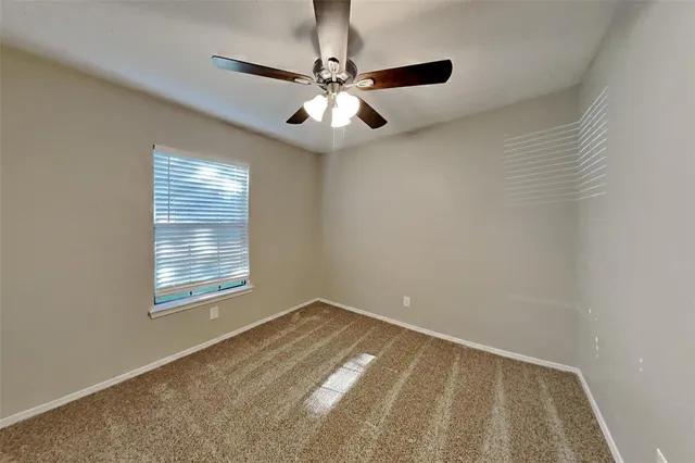 an empty room with a window and a fan