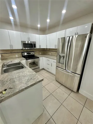 a kitchen with granite countertop a refrigerator and a sink