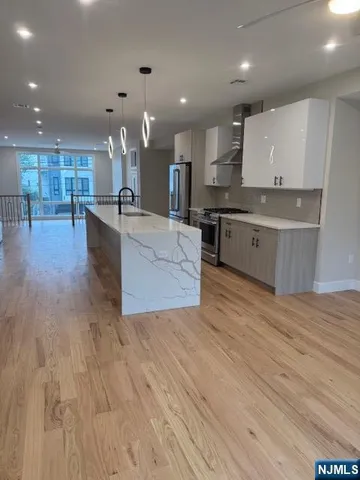 a large kitchen with stainless steel appliances kitchen island a large counter top and a wooden floors