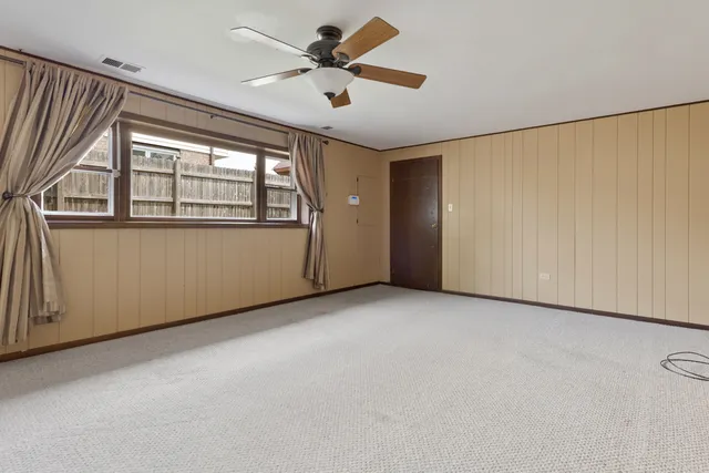 an empty room with windows and fan