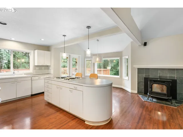 a kitchen with kitchen island granite countertop a stove a sink and white cabinets with wooden floors