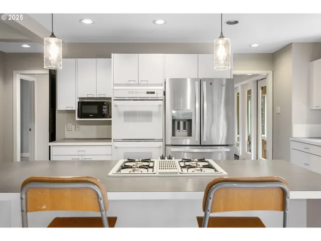 a kitchen with kitchen island granite countertop a sink cabinets and stainless steel appliances