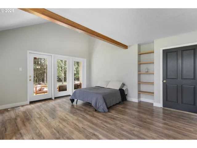 a spacious bedroom with a bed and wooden floor