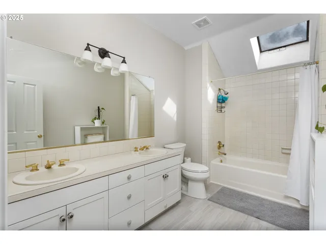a bathroom with a granite countertop sink a toilet a mirror and shower