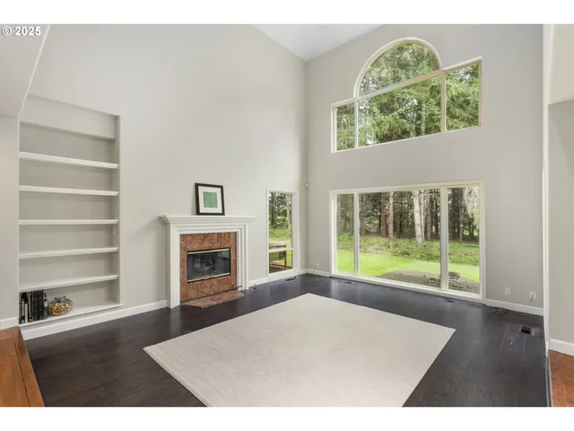 a view of an empty room with a fireplace and wooden floor