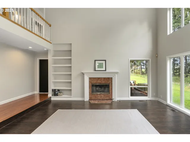 a view of an empty room with wooden floor fireplace and windows