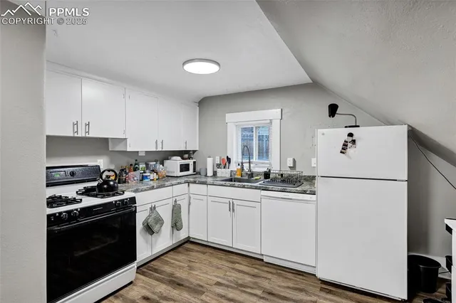 a kitchen with a sink a refrigerator and white cabinets