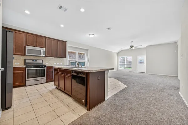 a kitchen with stainless steel appliances granite countertop a stove top oven a sink and a refrigerator