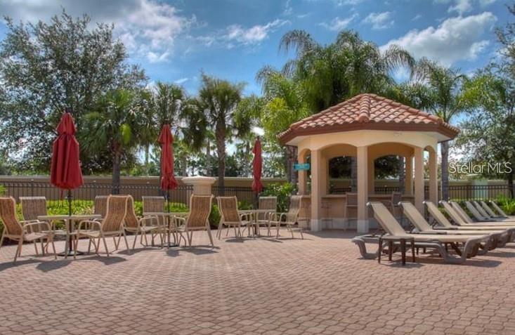 8153 Miramar Way Lakewood Ranch, FL 34202 - Photo 35 of 42 a view of a patio with table and chairs potted plants and a palm tree