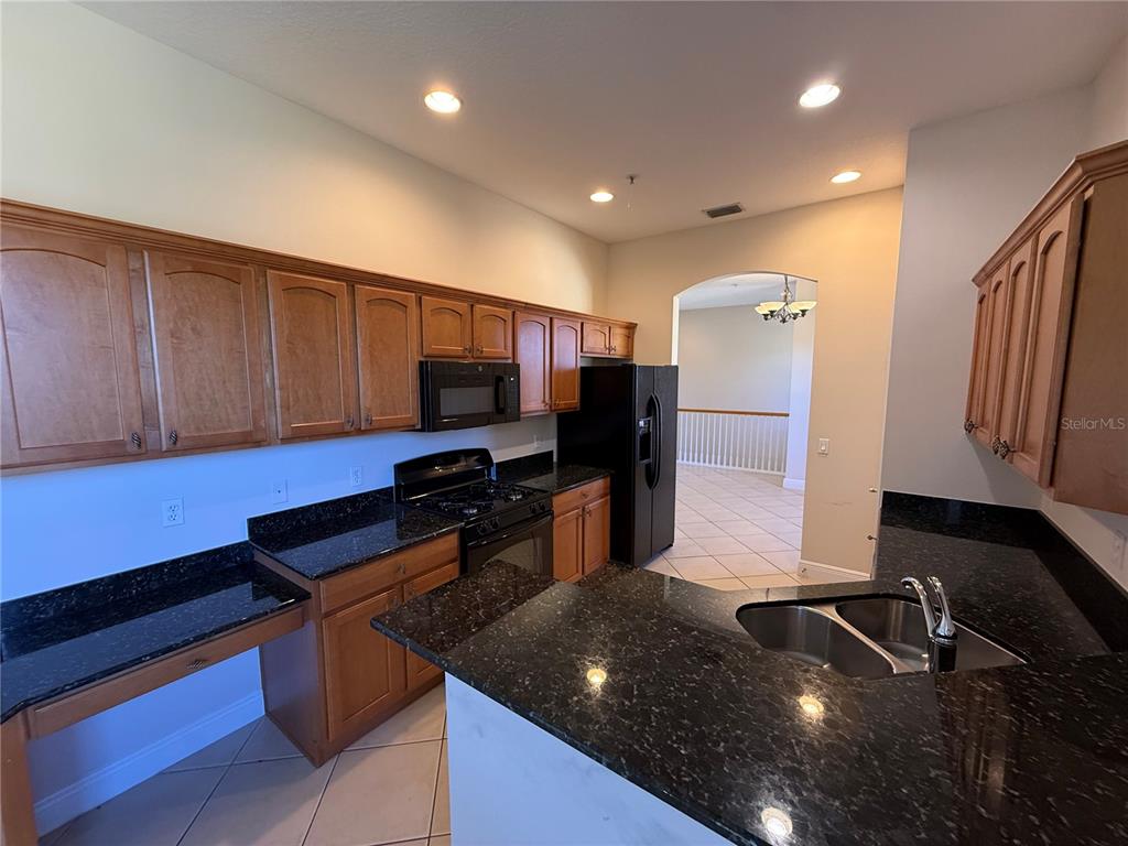 8153 Miramar Way Lakewood Ranch, FL 34202 - Photo 8 of 42 a kitchen with kitchen island granite countertop a sink and a stove top oven with wooden floor