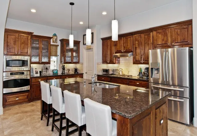 a kitchen with stainless steel appliances granite countertop a stove refrigerator sink and cabinets