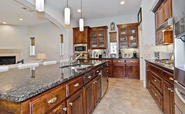 a kitchen with granite countertop a sink a counter top space appliances and cabinets