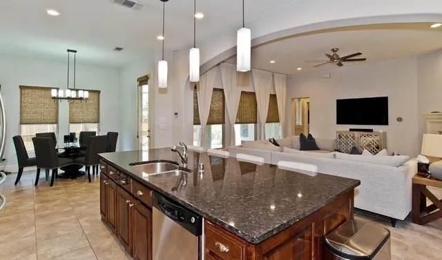 a large kitchen with kitchen island a stove a sink a counter space and living room view
