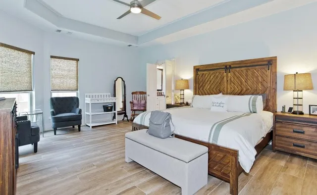 a bedroom with a bed a couch and wooden floor