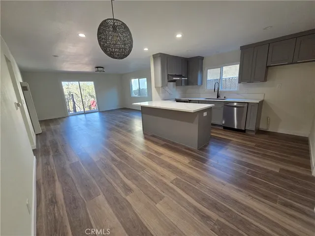 a large kitchen with hardwood floor a window and stainless steel appliances