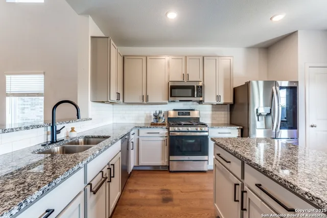 a kitchen with stainless steel appliances granite countertop a sink dishwasher a stove top oven a refrigerator with granite countertops and cabinets