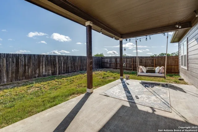 a view of backyard with a tub and wooden fence