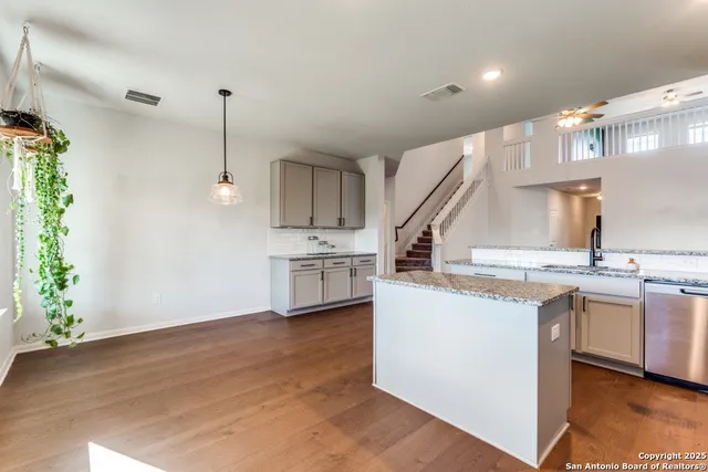 a kitchen with stainless steel appliances kitchen island granite countertop a sink a stove and a wooden floors