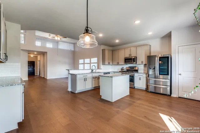 a large kitchen with white cabinets stainless steel appliances a sink and a center island