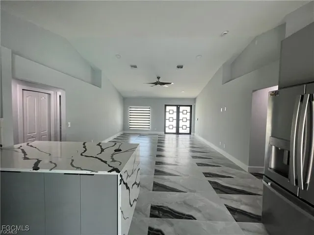a view of a refrigerator in kitchen and an empty room