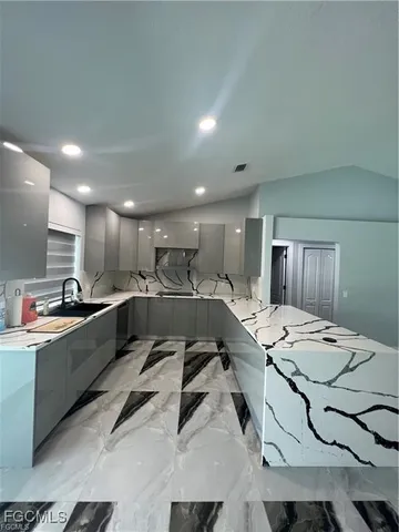 a large white kitchen with a sink table and chairs
