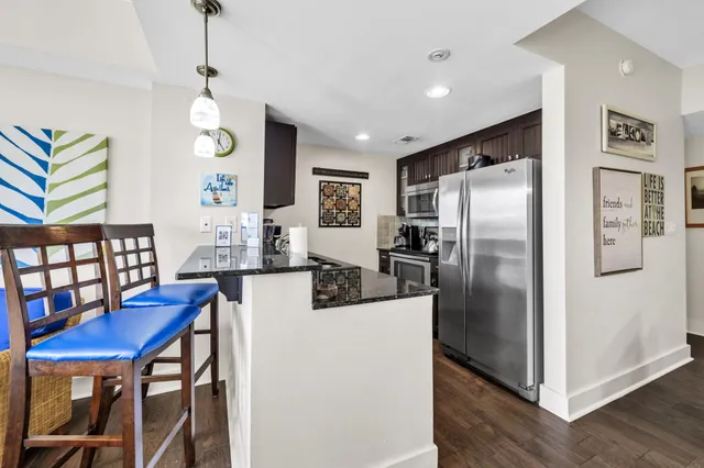 a kitchen with stainless steel appliances granite countertop a refrigerator a microwave a stove and white cabinets with wooden floor