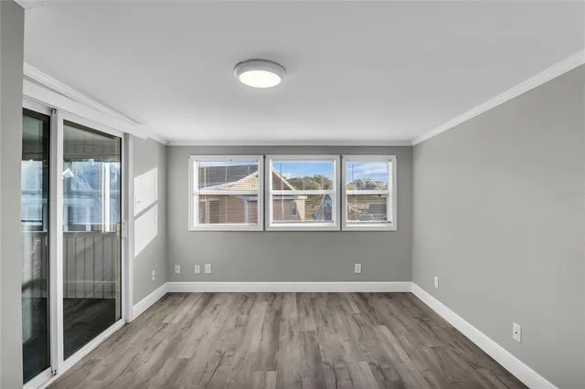 an empty room with wooden floor front door and windows