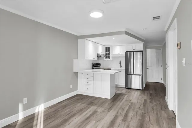 a kitchen with a refrigerator and white cabinets