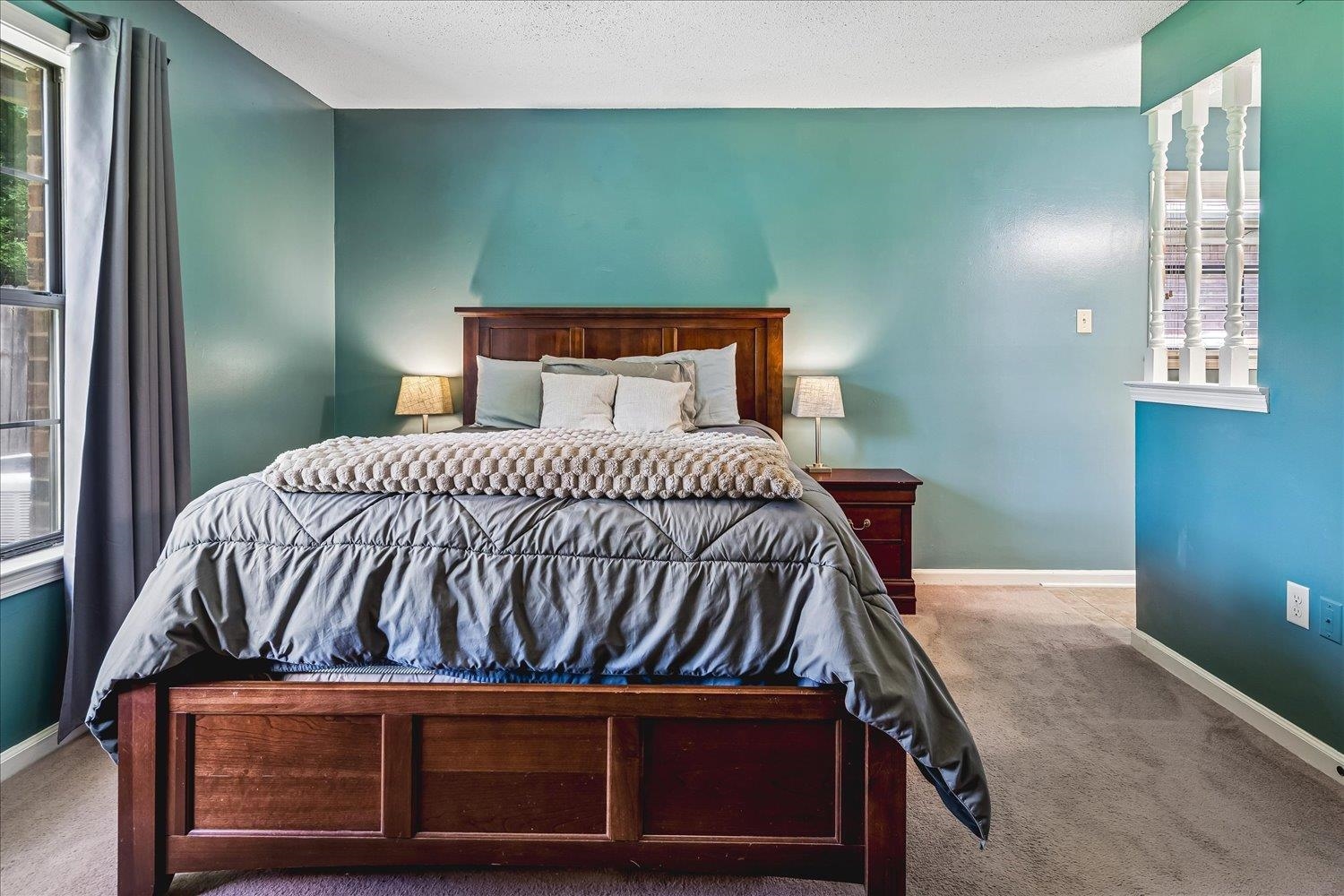 5711 Yale Road Bartlett, TN 38134 - Photo 14 of 29 Spacious bedroom featuring vibrant teal walls, a large window with privacy curtains, and soft carpet flooring