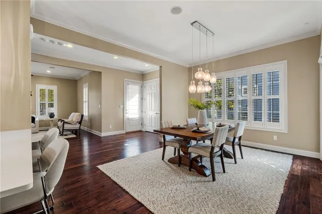 a dining room with wooden floor a chandelier a wooden table and chairs