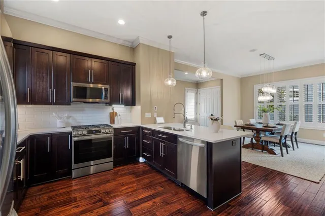 a kitchen with stainless steel appliances granite countertop wooden cabinets a sink dishwasher a stove and a refrigerator with wooden floor