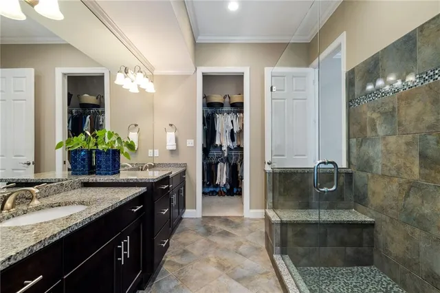 a spacious bathroom with a granite countertop sink a mirror and shower