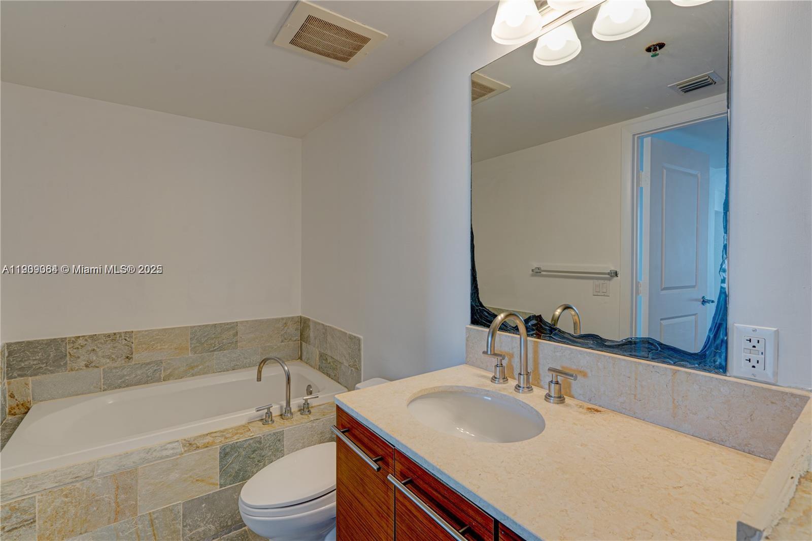 2641 North Flamingo Road, Unit 2307N Sunrise, FL 33323 - Photo 33 of 43 a bathroom with a sink a toilet a mirror and bathtub