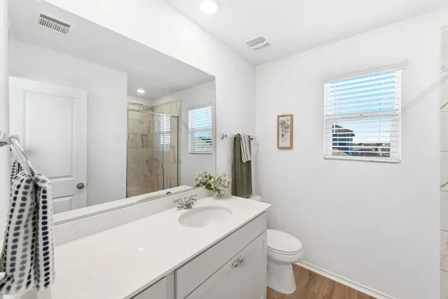 a bathroom with a toilet a sink a mirror a window and vanity