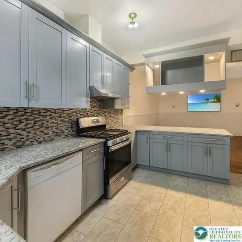 a large kitchen with kitchen island granite countertop a stove a sink and a refrigerator