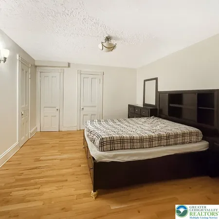 a bedroom with a bed and a chair with wooden floor
