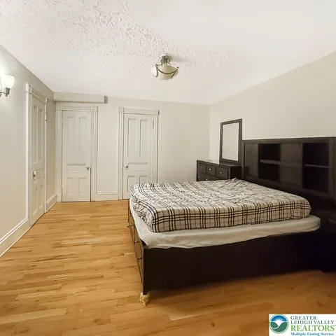 a bedroom with a bed and a chair with wooden floor