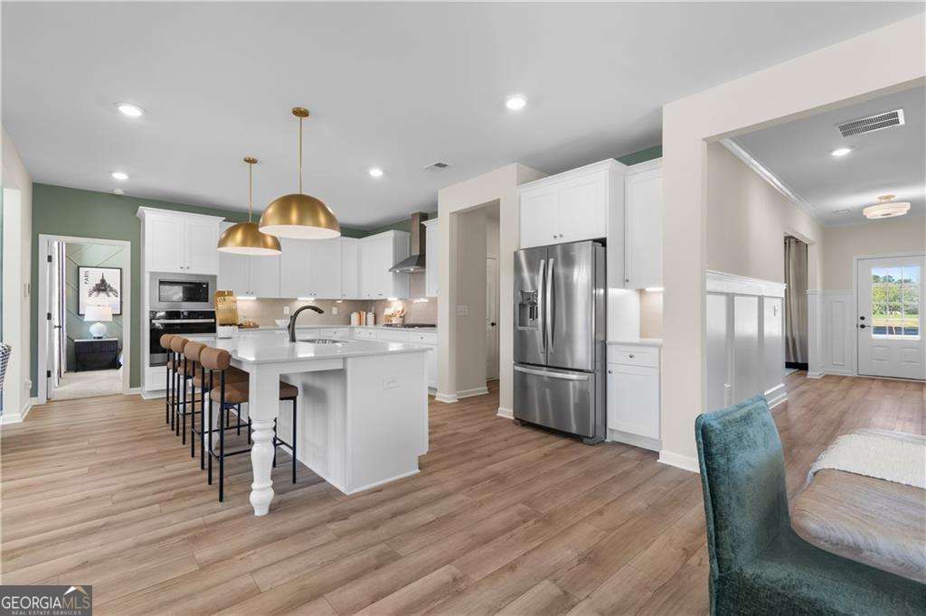 420 Hartsfield Road McDonough, GA 30253 - Photo 14 of 44 a kitchen with stainless steel appliances kitchen island granite countertop a refrigerator a stove a sink a dining table and chairs with wooden floor