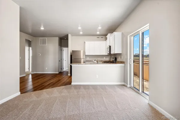 a view of kitchen with refrigerator and white cabinets