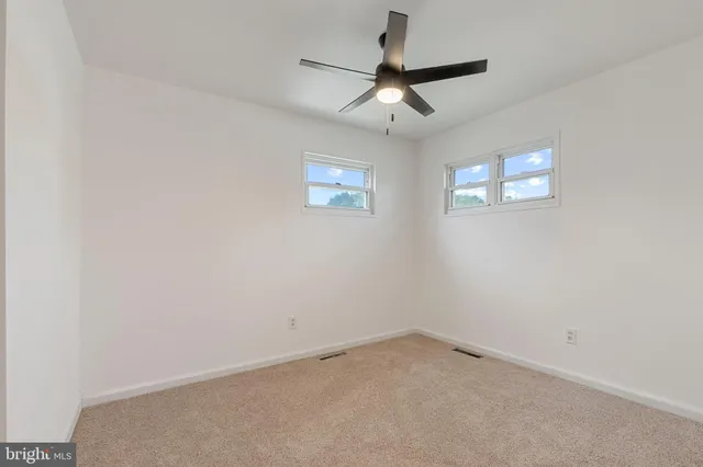 an empty room with a ceiling fan and carpet