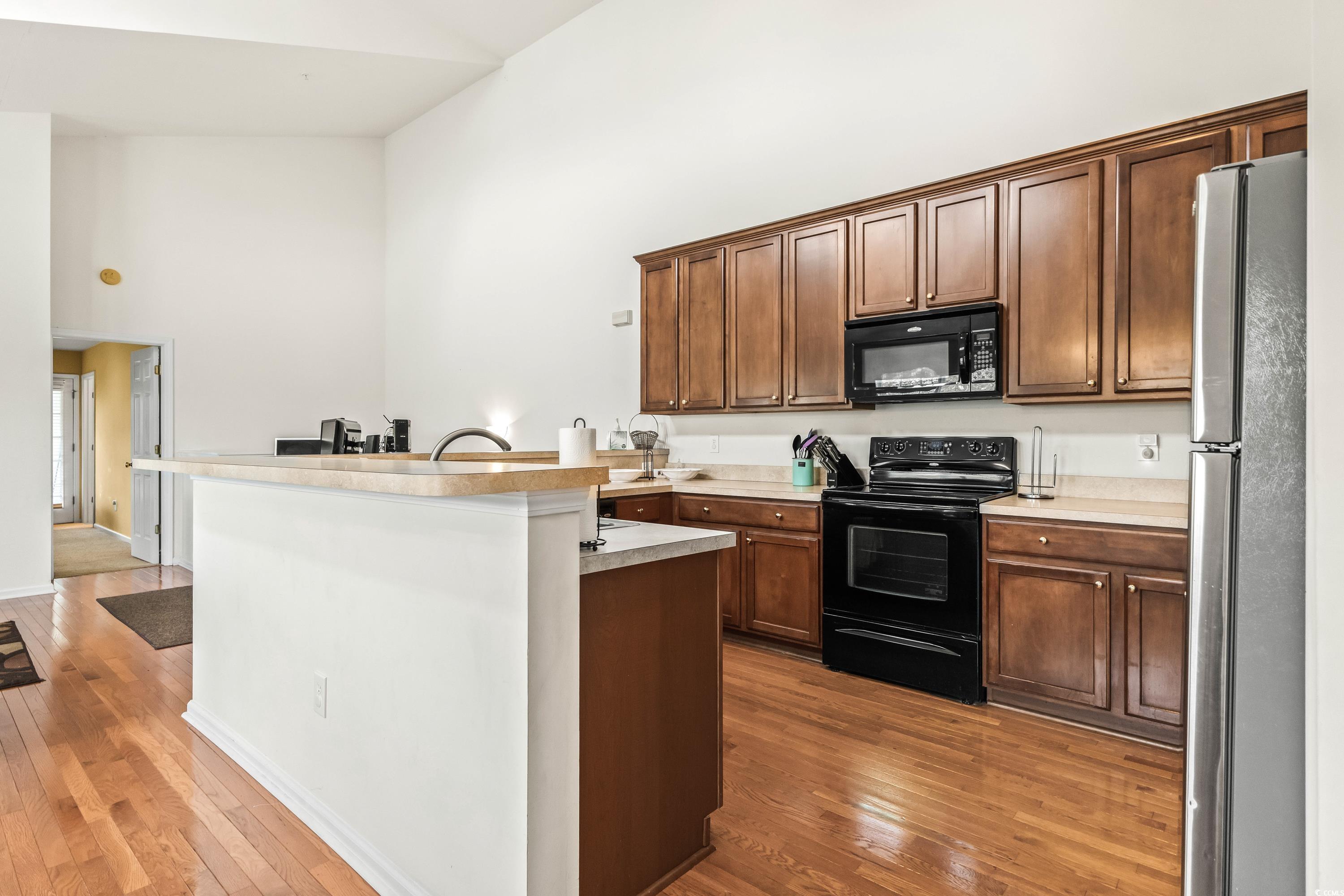 400 Black Smith Lane, Unit A Myrtle Beach, SC 29579 - Photo 12 of 35 Kitchen with black appliances, light countertops, a high ceiling, dark wood finished floors, and an island with sink
