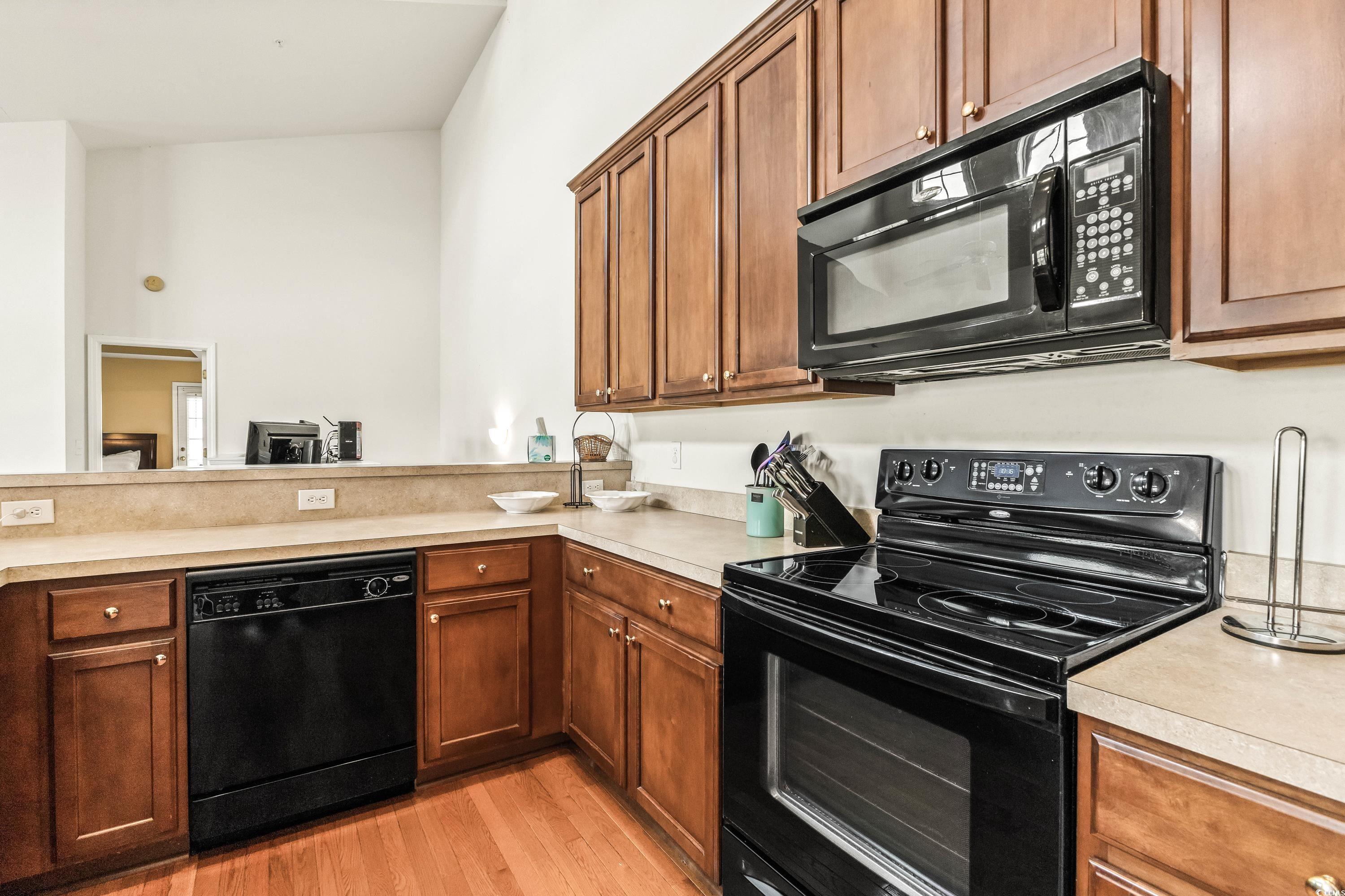 400 Black Smith Lane, Unit A Myrtle Beach, SC 29579 - Photo 14 of 35 Kitchen featuring black appliances, light countertops, light wood-type flooring, and brown cabinets
