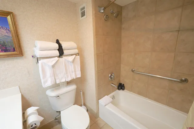 a bedroom with a bed a chair and a flat screen tv