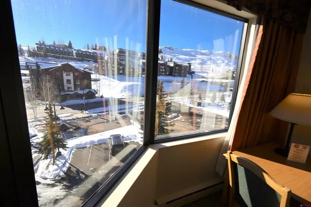 a living room with stainless steel appliances furniture a rug and a kitchen view