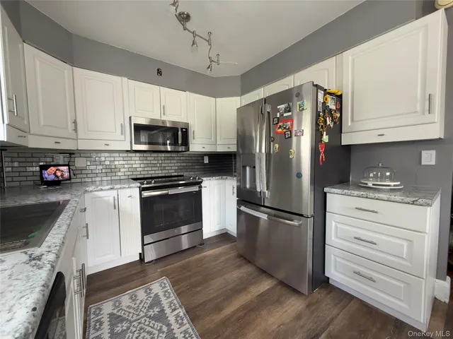 a kitchen with stainless steel appliances granite countertop a refrigerator stove a sink and dishwasher with wooden floor