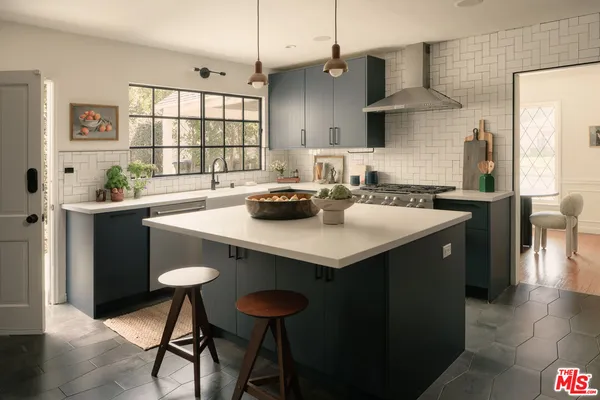 a kitchen with a sink a stove and chairs with wooden floor
