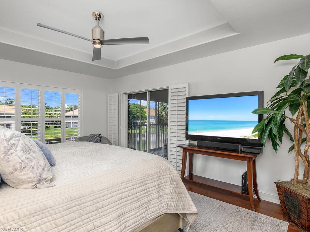 816 Carrick Bend Circle, Unit 202 Naples, FL 34110 - Photo 32 of 50 Bedroom with a raised ceiling, hardwood floors, and multiple windows